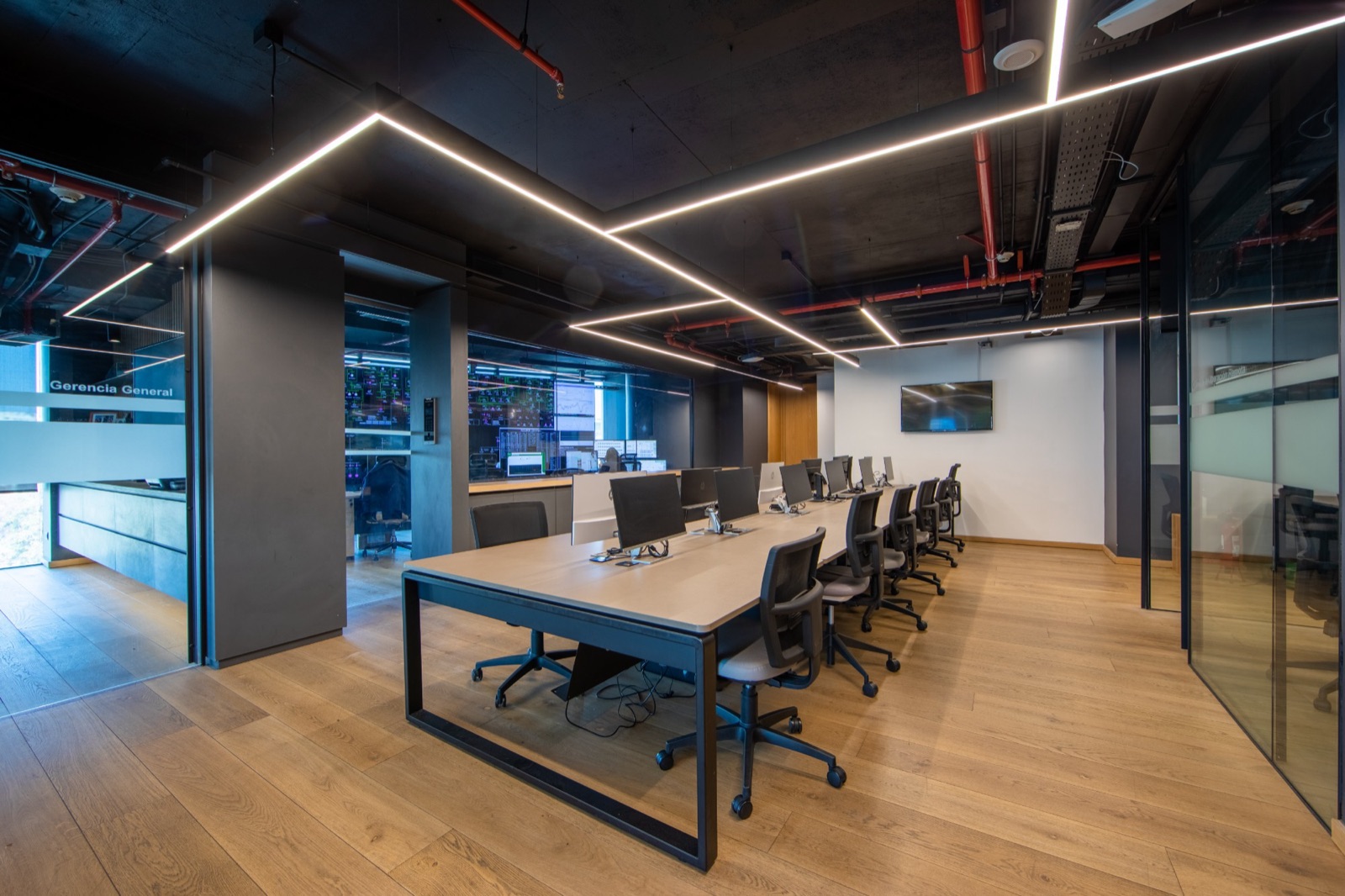 Espacio de trabajo central de las oficinas Enlasa, con iluminación lineal y piso de madera