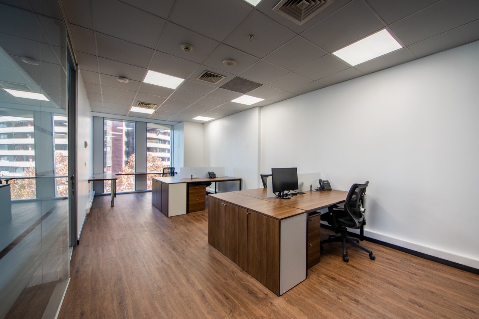 Oficina con puestos de trabajo, piso de madera y ventanales en Olá Hotel