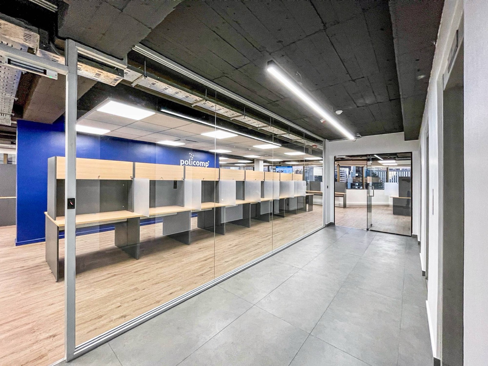 Acceso al call center Policomp con muro de vidrio y muro azul con el logo de la marca